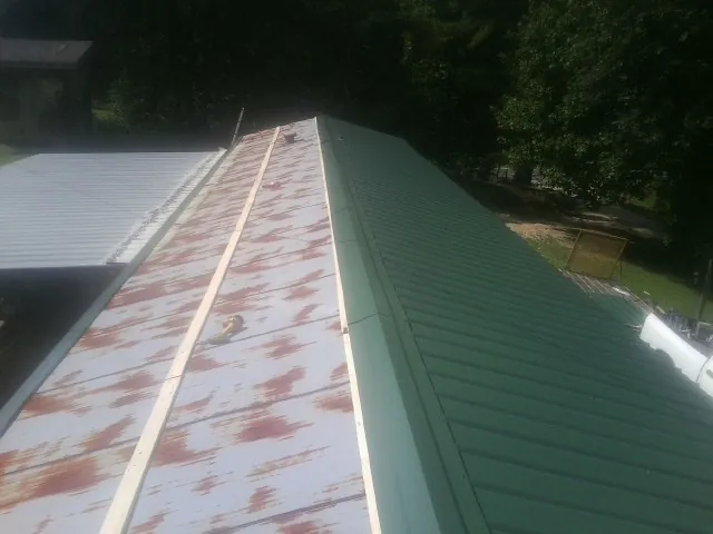 Old rusted panels beside newly installed green metal roofing — Wind Damage Roof Repair by Roofing Brothers in Oakdale