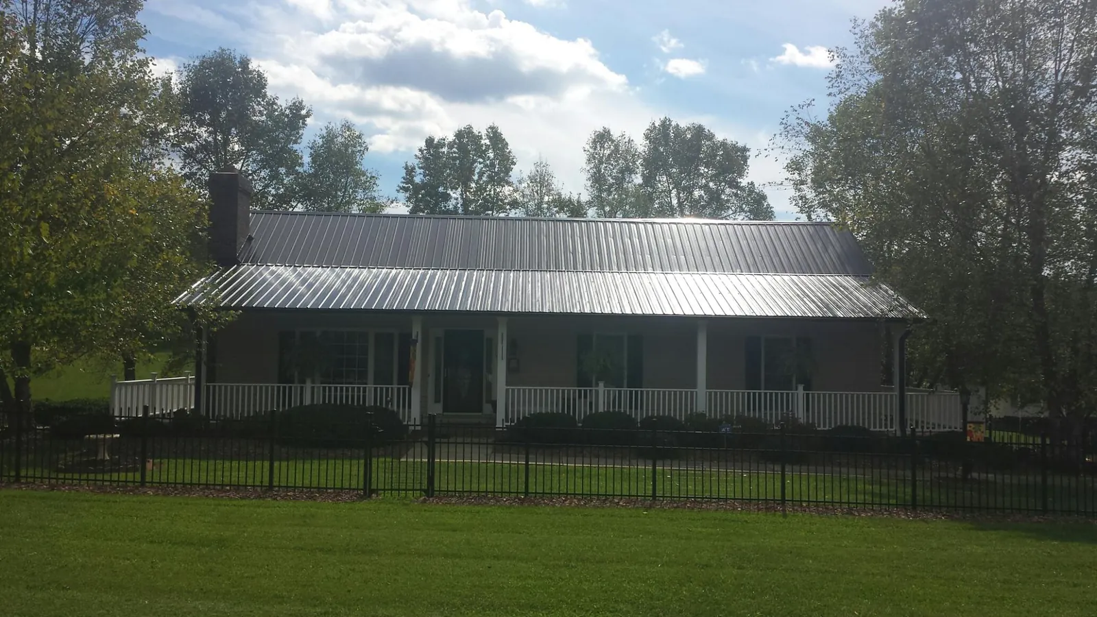 Gray metal roof on a brick ranch with a full width front porch — Gutter Guard Installation work by our crew in Oakdale